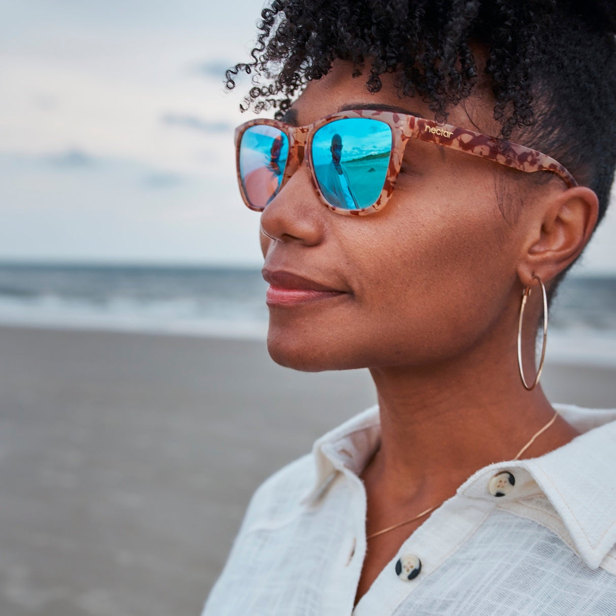 Woman wearing sunglasses with a beach in the background