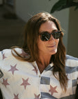 Woman wearing sunglasses and a star-patterned shirt in an outdoor setting