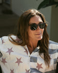 Woman wearing sunglasses and a star-patterned shirt in an outdoor setting