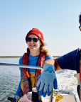 Two people on a boat in the water, wearing life vests and sunglasses.