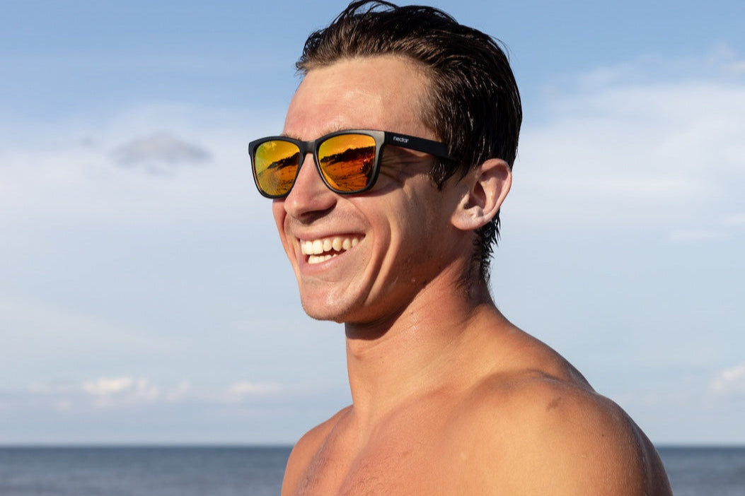 Man wearing sunglasses on a beach with ocean and sky in the background