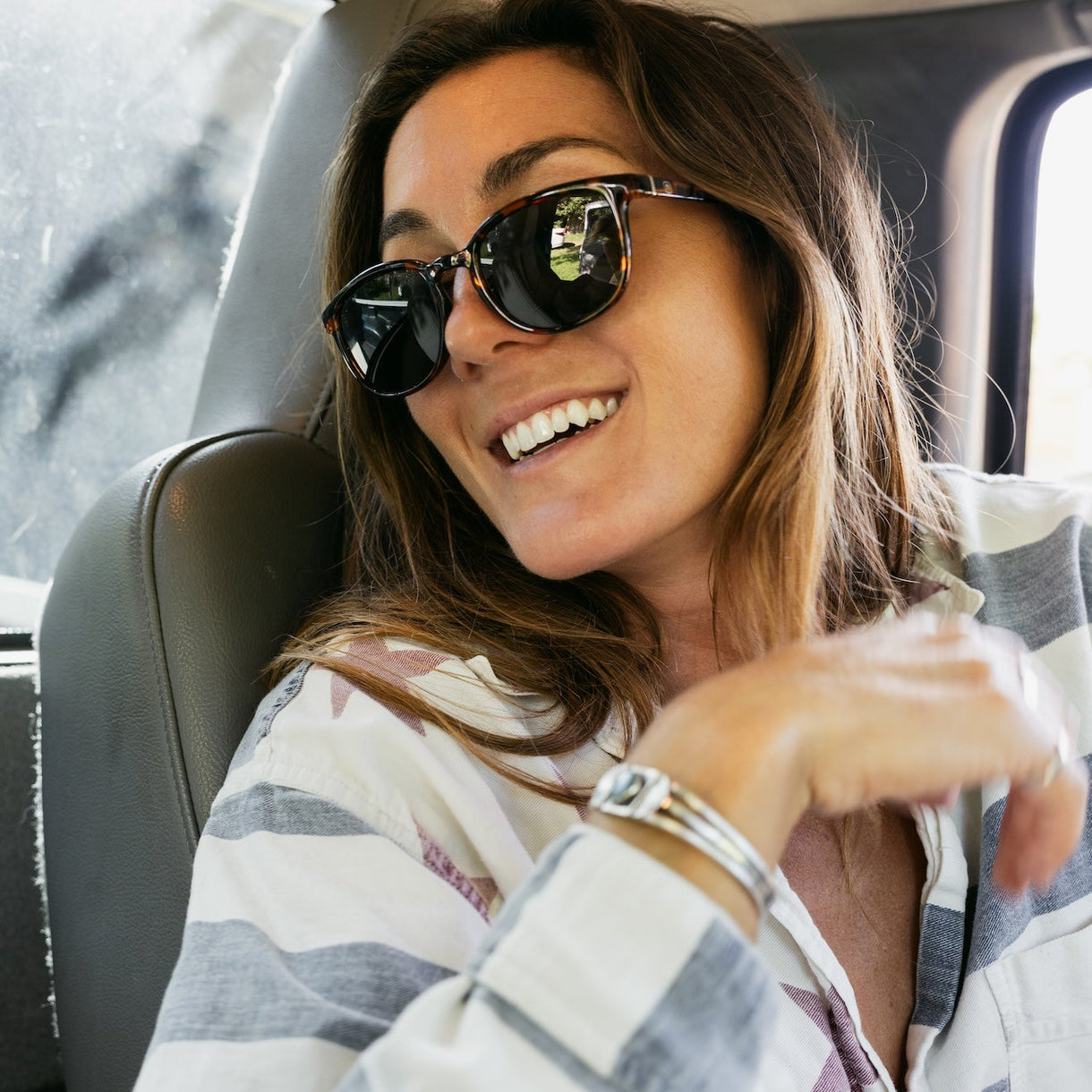Woman wearing sunglasses and a plaid shirt inside a vehicle