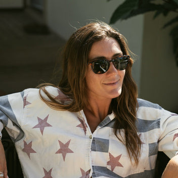 Woman wearing sunglasses and a star-patterned shirt in an outdoor setting